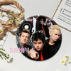 A set of collectible button pins featuring members of the punk band Green Day on an album cover design.