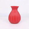 A vibrant red ceramic flower vase with vertical ribbed texture.