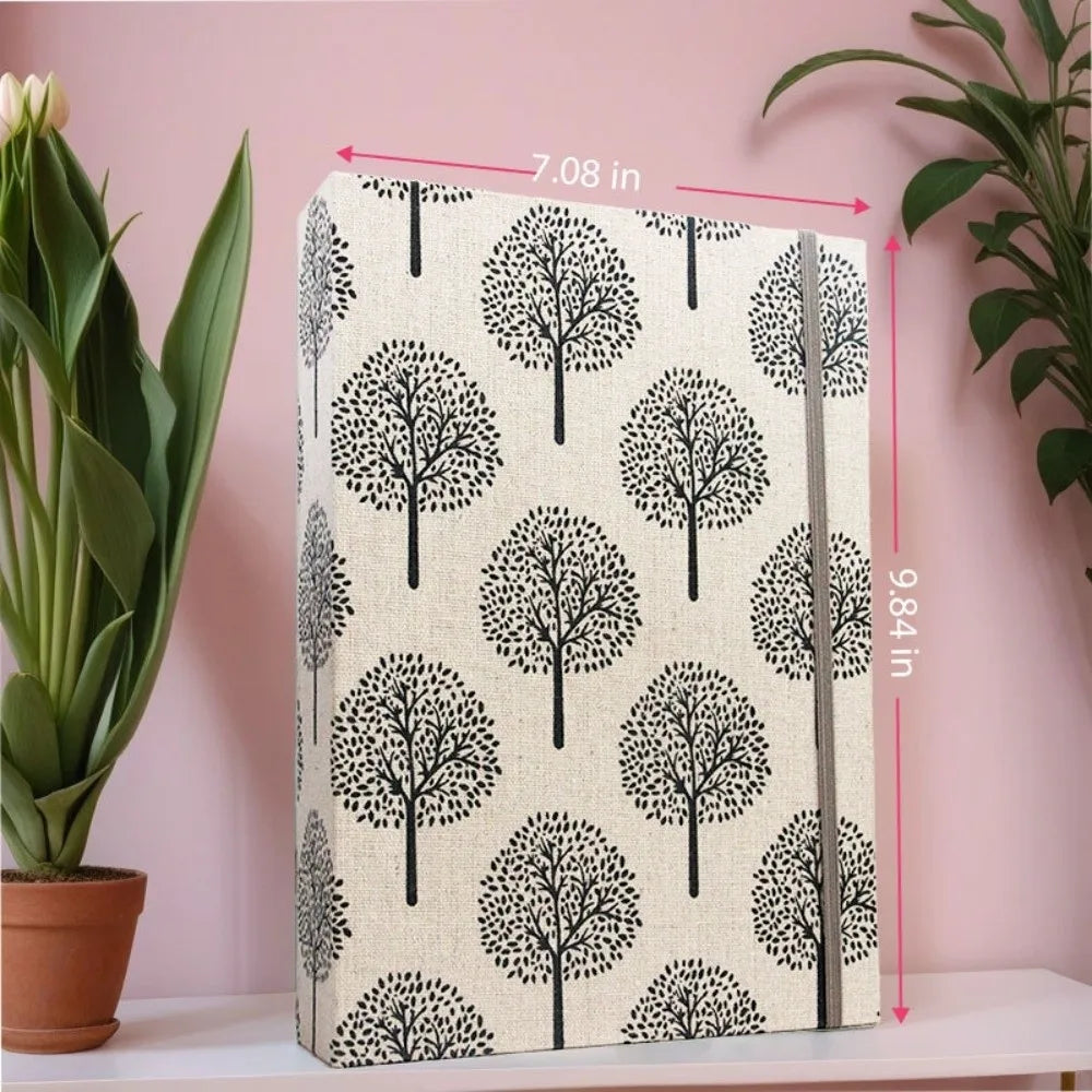Álbum de recortes de tela vertical con patrón de árbol blanco y negro, mostrado contra una pared rosa.