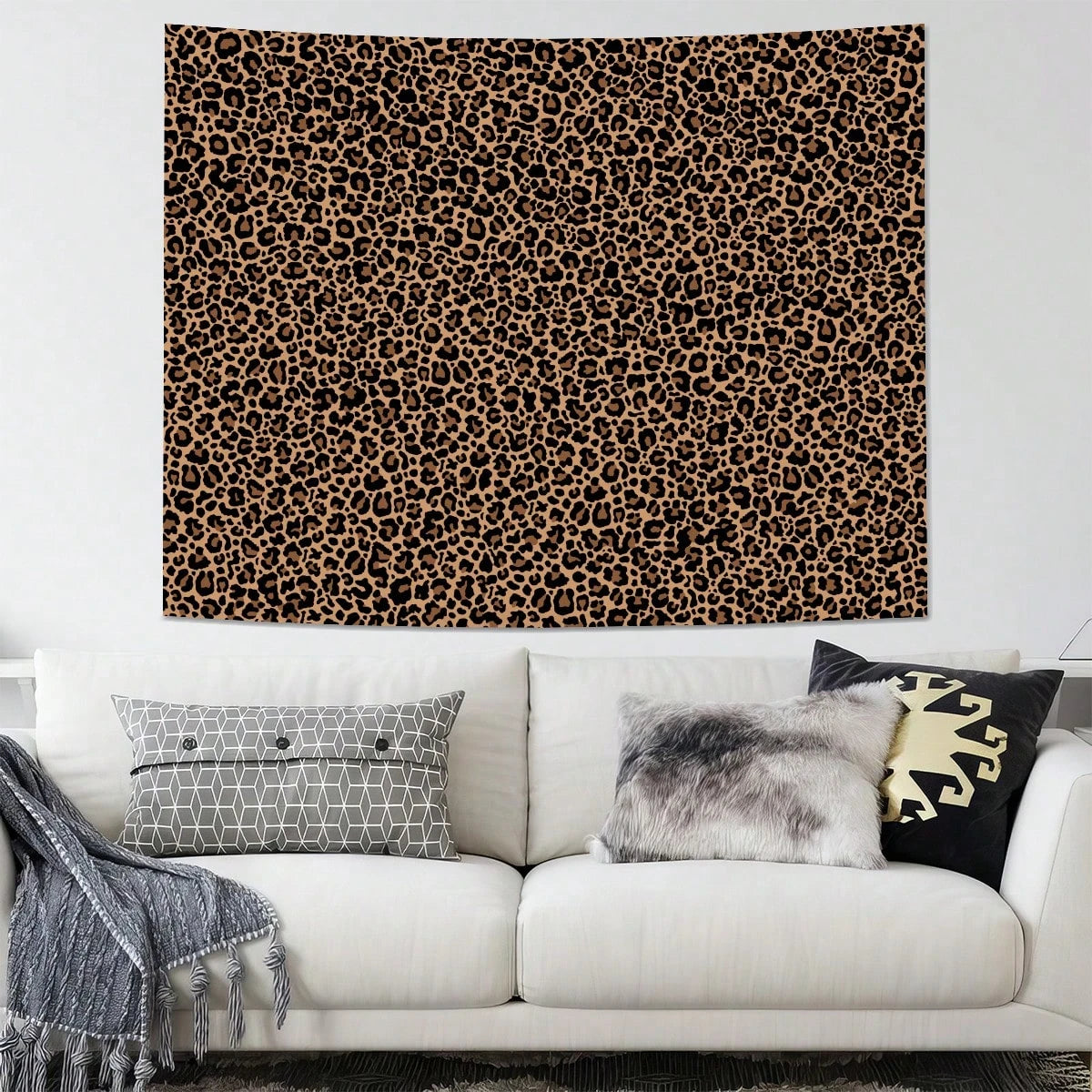 A leopard print tapestry wall hanging displayed above a white sofa with decorative pillows.