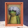 A cute green frog character is displayed inside a wooden photo frame.