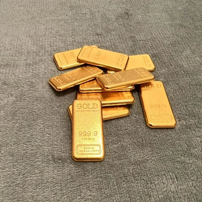 A set of ten simulated gold ingots or fortune charms arranged on a dark gray fabric surface.