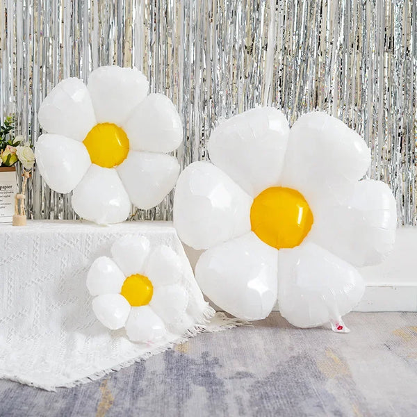 A cluster of white and yellow aluminum foil balloons arranged in a daisy shape against a silver textured background.