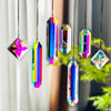A set of seven colorful crystal prism sun catchers hanging by strings against a blurred green background.