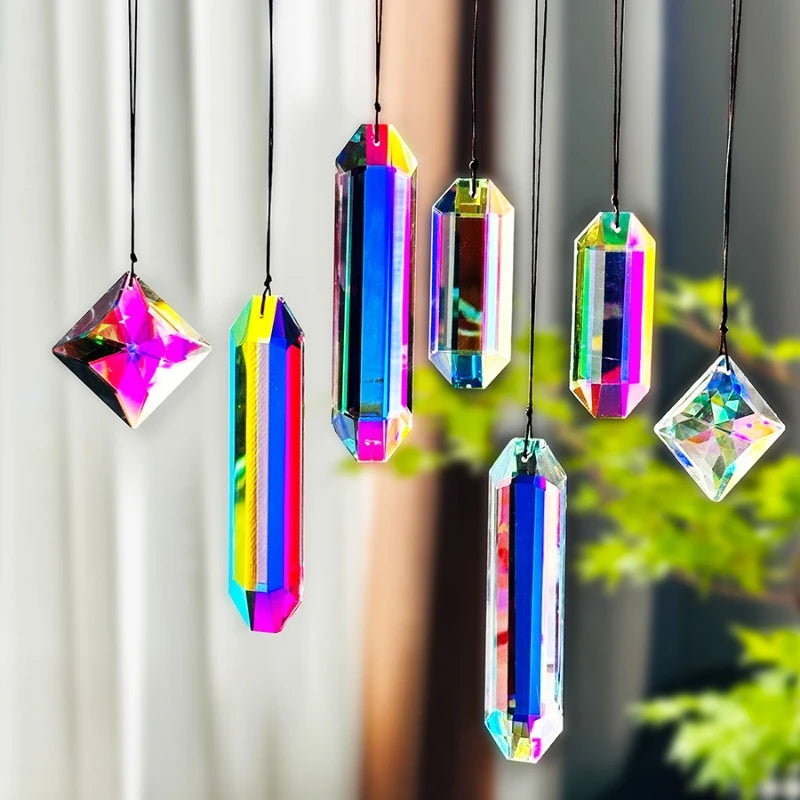 A set of seven colorful crystal prism sun catchers hanging by strings against a blurred green background.