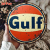Vintage round metal sign with an orange and blue design featuring the word Gulf