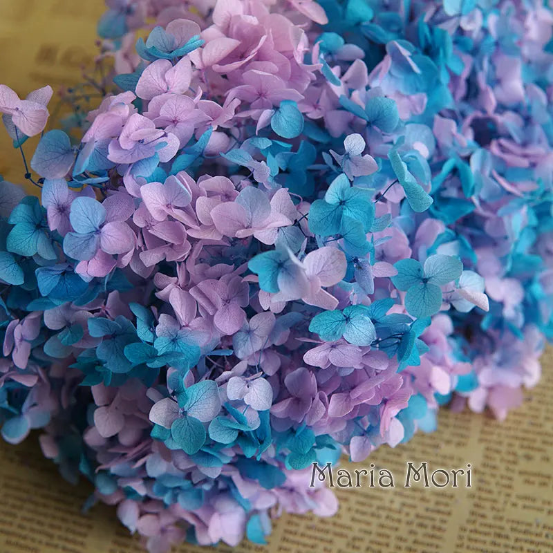 A dense bouquet of handmade dried hydrangea flowers in shades of purple and blue.