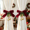 Festive Christmas curtain tie-backs with red bows and pinecones displayed in a bright room.