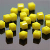 A collection of square cut yellow glass crystal beads arranged in a row on a dark surface.