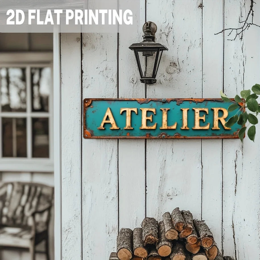A vintage industrial metal wall sign with the word ATELIER in turquoise and golden distressed colors mounted on white wooden 