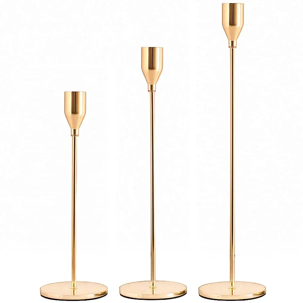 A set of three elegant gold-toned metal candle holders with tall slender stems.