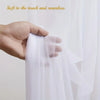 A hand gently touches sheer white tulle fabric used as a backdrop or curtain.