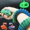 Eine Hand hält ein grünes 3D-gedrucktes Schlangen-Fidget-Spielzeug mit verschiedenen bunten Schlangen darunter ausgestellt.