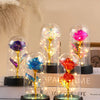 A glass dome featuring an eternal rose with a golden LED light displayed on a black base.