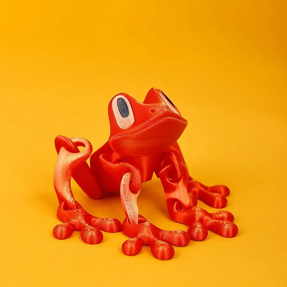 A bright orange tree frog ornament with vibrant red skin and large eyes is displayed against a solid orange background.