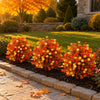 Bola de topiary artificial de caja en naranja y amarillo vibrante plantada en un jardín.