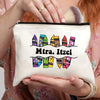 A beige canvas makeup bag with colorful geometric shapes and text on it is held by a person.