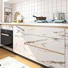 White kitchen cabinets with gold marble contact paper and modern appliances on a countertop