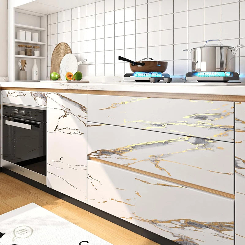White kitchen cabinets with gold marble contact paper and modern appliances on a countertop