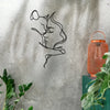 Black metal wall art silhouette of a woman and cat embracing on a gray concrete wall.