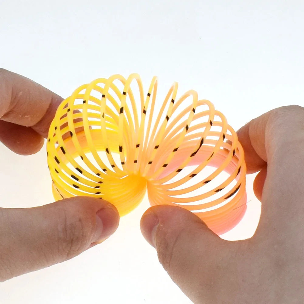 A hand holds a bright yellow and orange spring toy with numerous thin, black filaments.