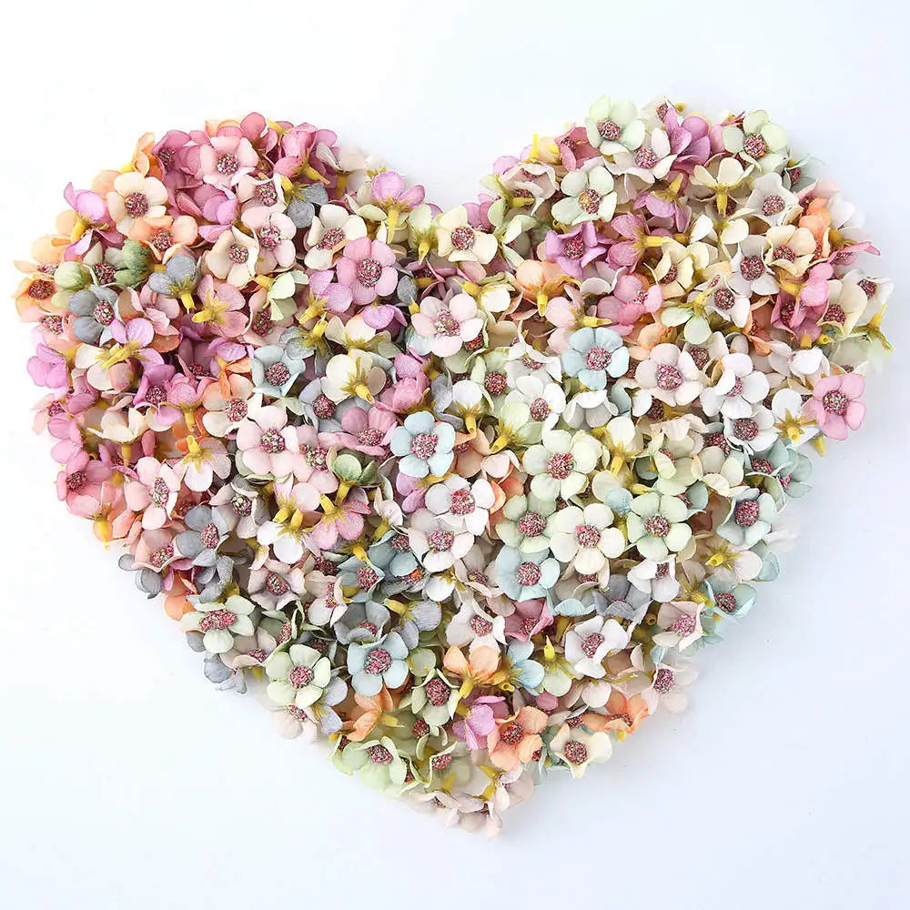 A heart-shaped arrangement of pink, white, and green silk artificial flower heads for decor.