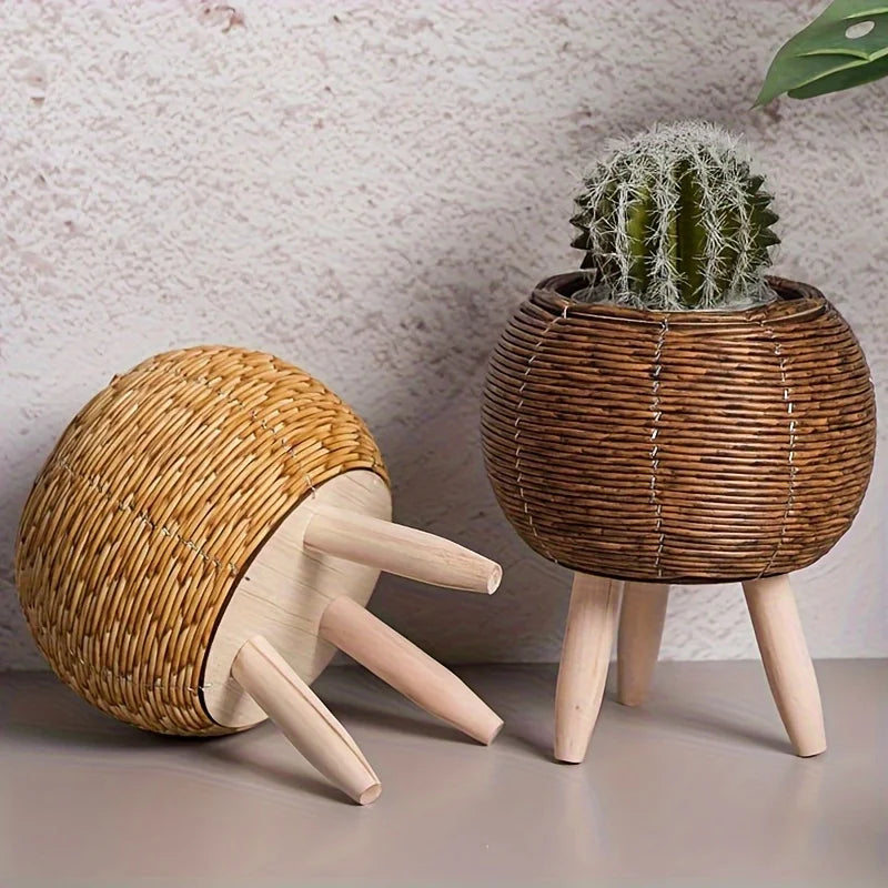 A rustic rattan planter with a cactus sits on wooden legs against a light background.