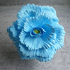 A vibrant light blue silk foam rose with layered petals and a green center.