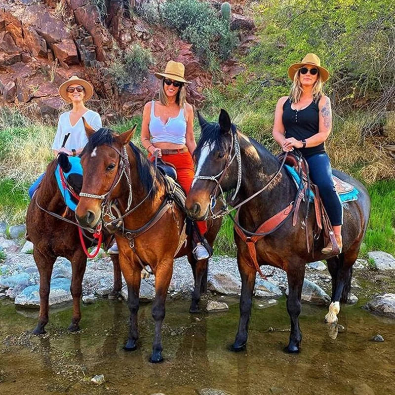 Three women posing with horses in a natural outdoor setting
