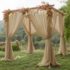 A beige chiffon backdrop curtain draped over a wooden frame for an outdoor wedding or event setting.