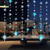 A vertical string of glittering star and polka dot lights hanging in the air.