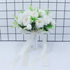 Elegant white silk rose bridal bouquet tied with a sheer ribbon against a black and white grid background