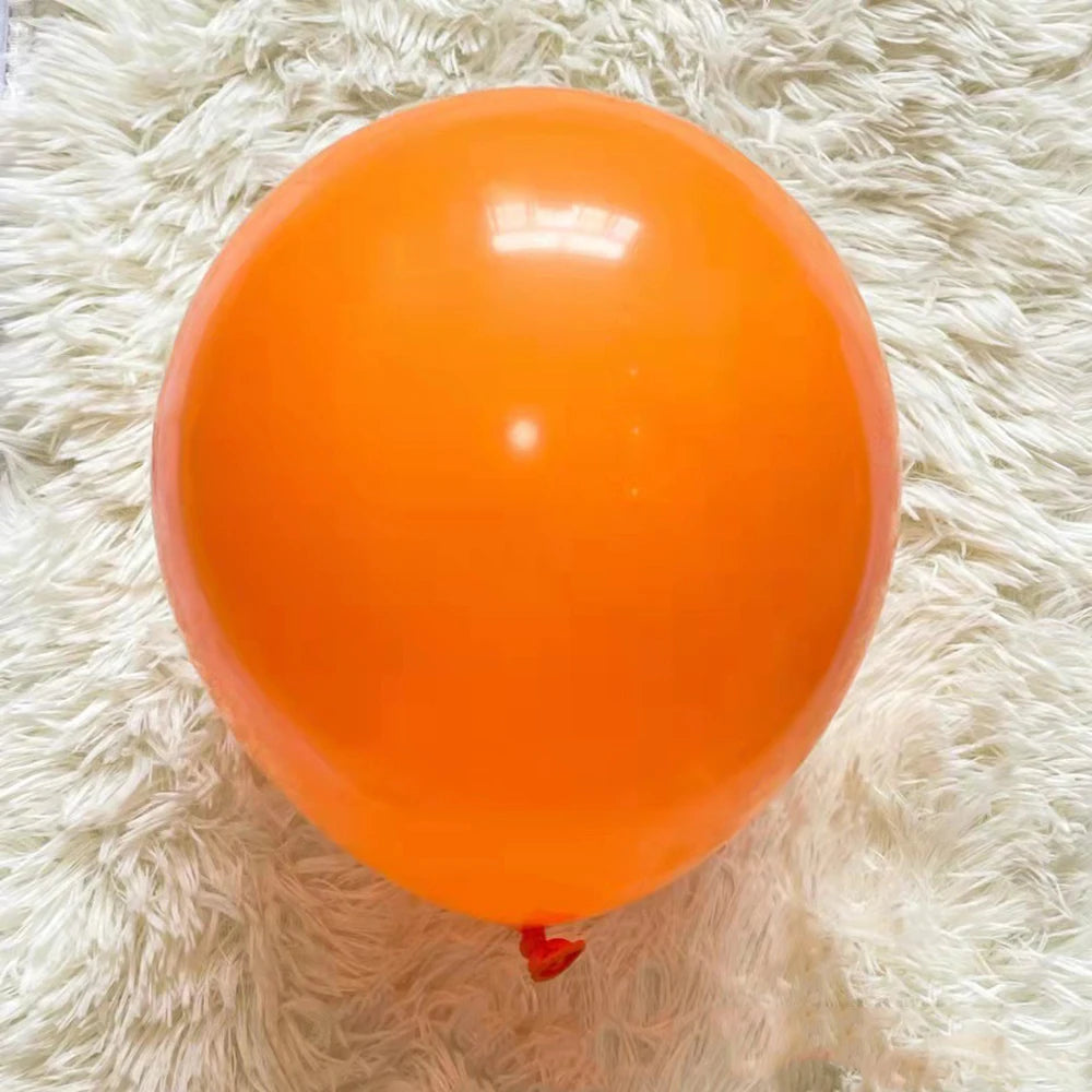 A single, round, bright orange latex balloon resting on a white, fluffy surface.