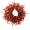 An artificial eucalyptus wreath with reddish-orange foliage used for autumn decor.