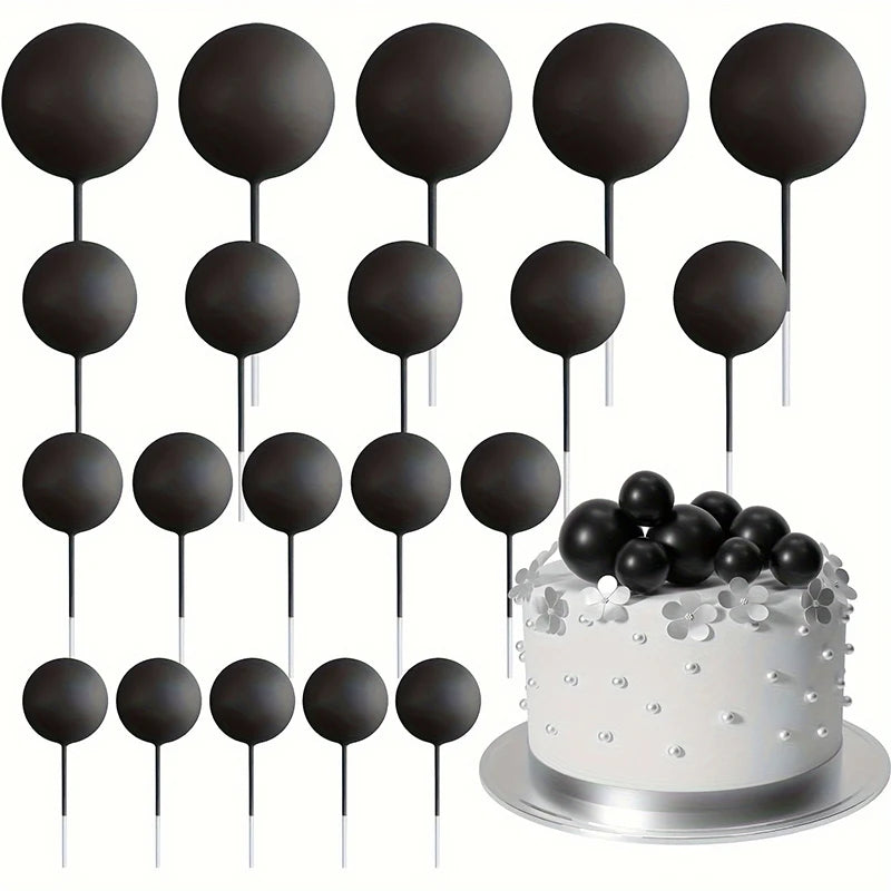 A set of twenty black ball cake toppers on sticks displayed above a silver cake.