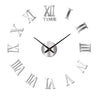 A silver acrylic wall clock face showing the time XII and various Roman numerals.