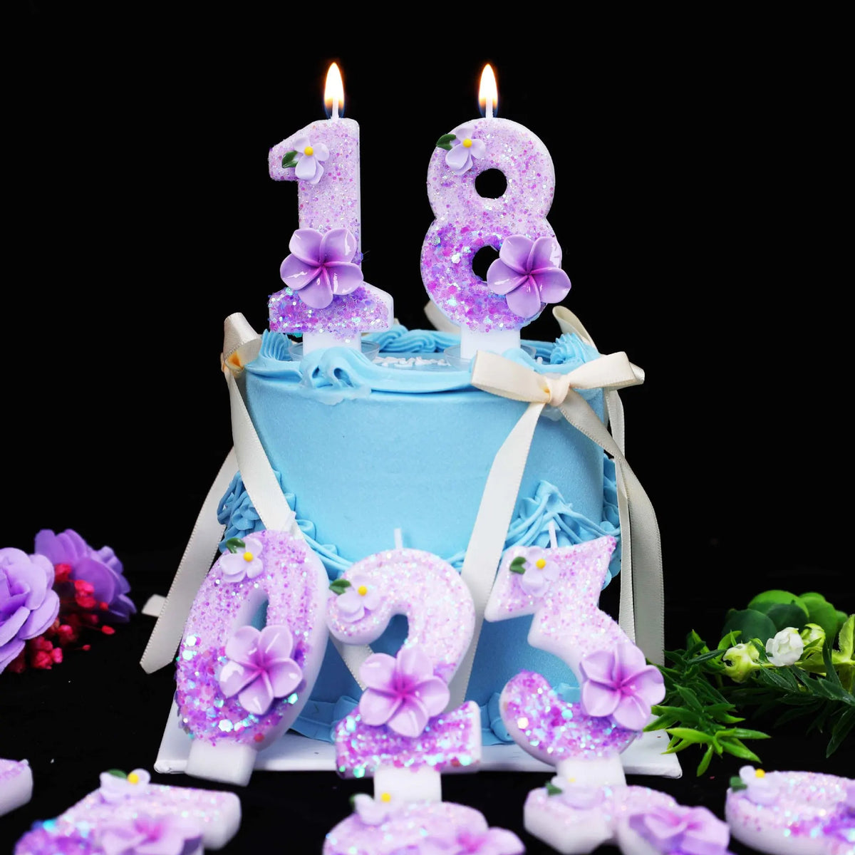 A birthday cake decorated with purple glitter flower number candles, including 18 and 23.