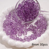 A small glass bowl filled with purple round spacer beads for jewelry making