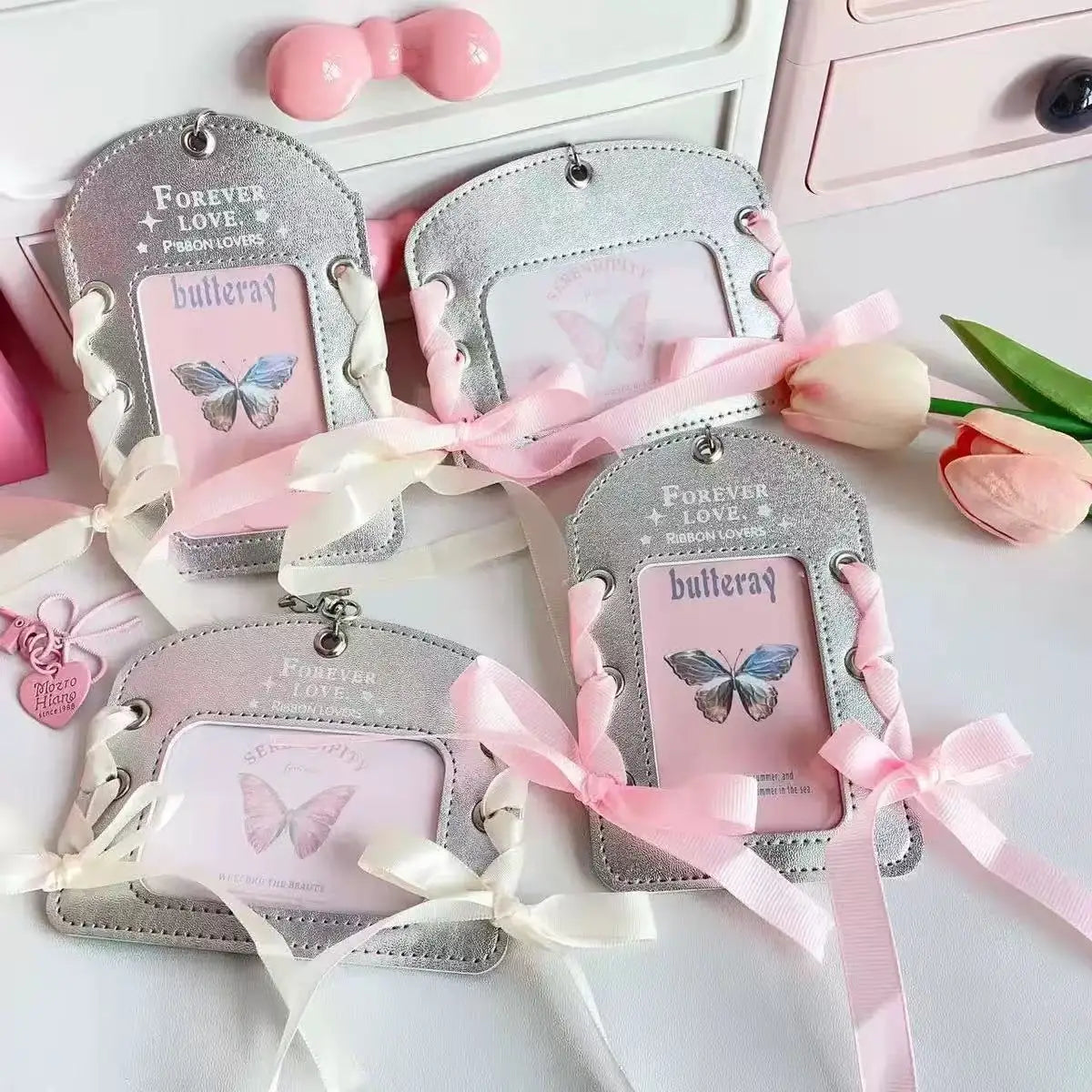 Silver lace PU card holders with pink and white bow ribbons displayed on a white surface.