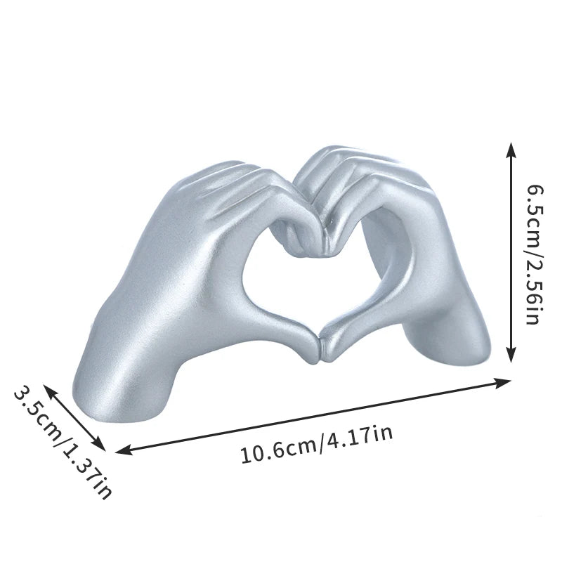 Silver heart shape sculpture made from two hands forming a heart, measuring 6.5cm high and 10.6cm wide.