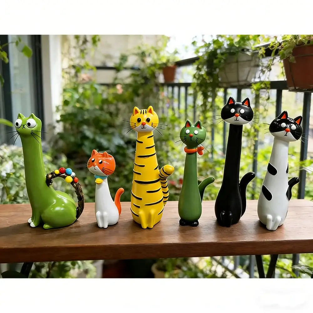 A collection of seven cat-shaped resin figurines in various colors and poses displayed on a wooden table.