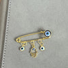 Elegant gold and silver evil eye brooch pin featuring an eye and a hand charm.