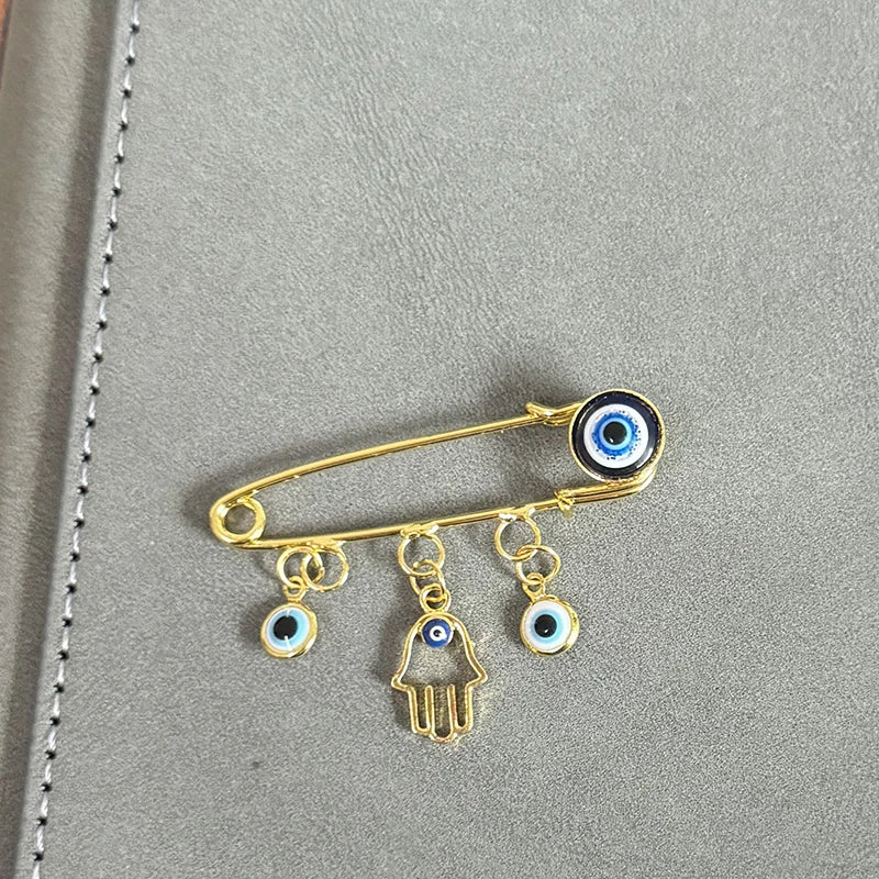 Elegant gold and silver evil eye brooch pin featuring an eye and a hand charm.