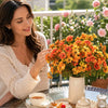 A woman is gently touching a bouquet of vibrant artificial pansy flowers in an outdoor setting.