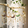 A display of ten moon-shaped crystal suncatchers hanging from a branch, labeled A through E.
