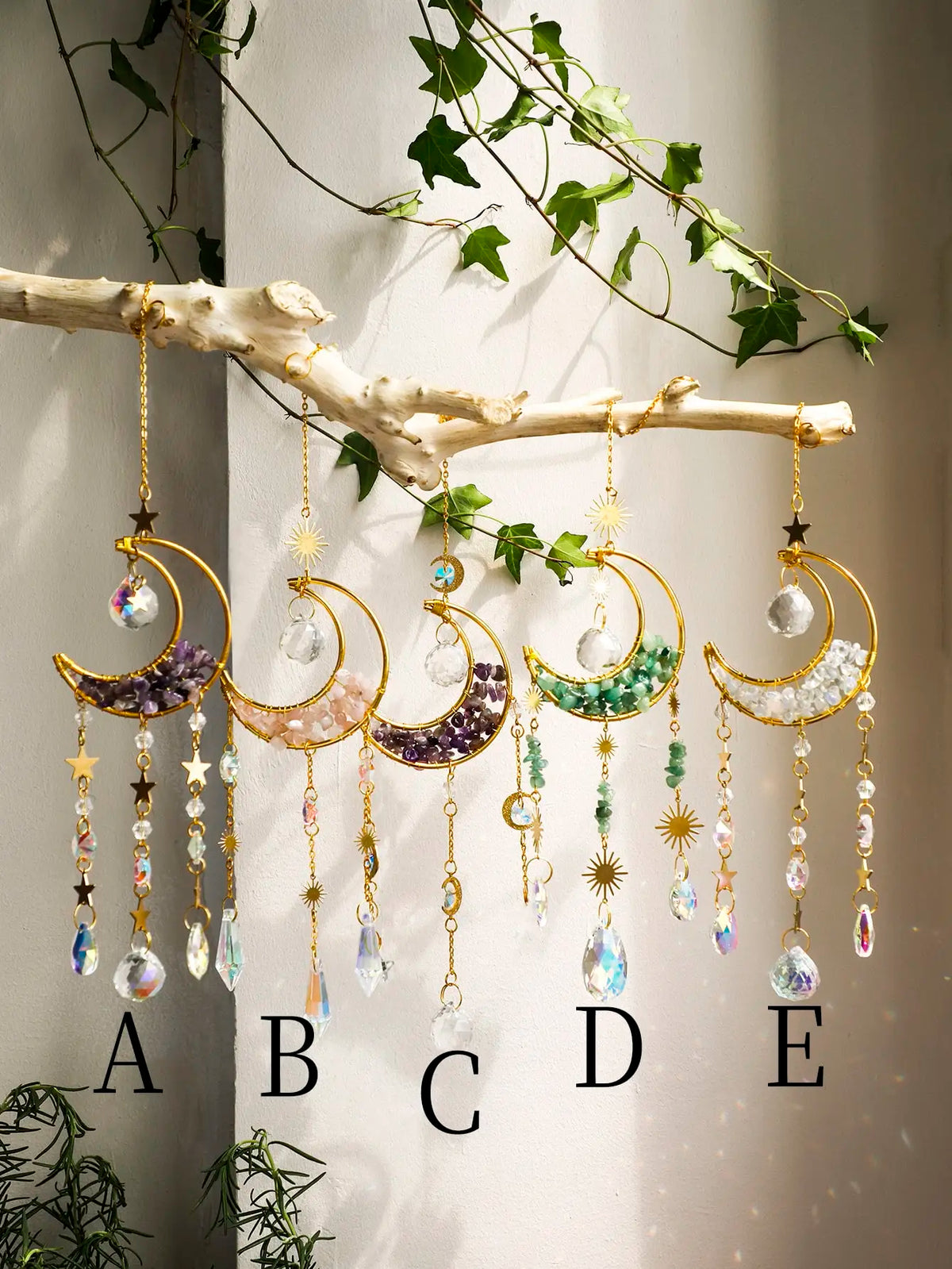 A display of ten moon-shaped crystal suncatchers hanging from a branch, labeled A through E.