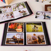 A black linen-cover photo album displaying several framed wedding and portrait photographs.