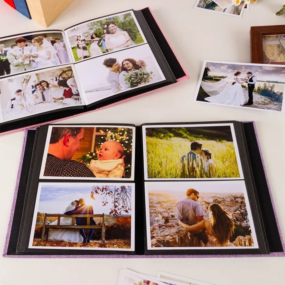 A black linen-cover photo album displaying several framed wedding and portrait photographs.