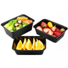 Three black plastic food storage containers filled with fresh fruit and vegetables like strawberries, avocado, and citrus sli