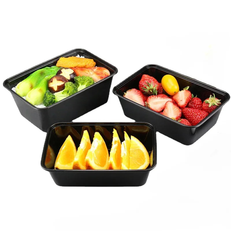 Three black plastic food storage containers filled with fresh fruit and vegetables like strawberries, avocado, and citrus sli